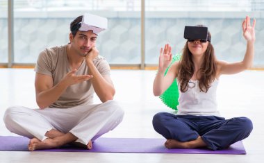 VR gözlüklü kadın ve erkek meditasyon yapıyor.