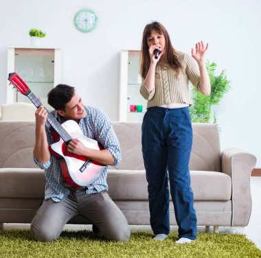 Genç bir aile evde şarkı söylüyor ve müzik çalıyor.