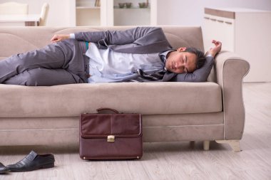 Yorgun genç işadamı işten sonra eve geliyor.