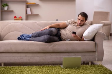 Evdeki kanepede yatan genç adam.