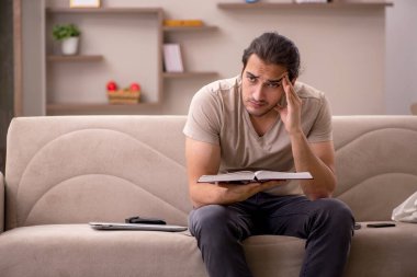 Evde kitap okuyan genç bir erkek öğrenci.