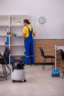 Genç müteahhit ofisi temizliyor.