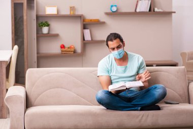 Genç erkek öğrenci salgın sırasında evde çalışıyor.