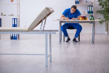 Genç erkek doktor hastanede not alıyor.