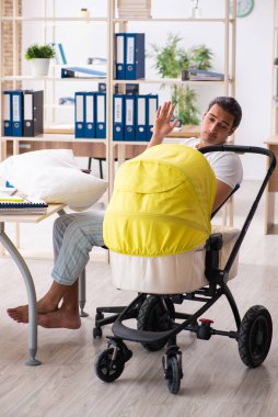 İş yerinde yeni doğan bebeğe bakan genç bir erkek işçi.