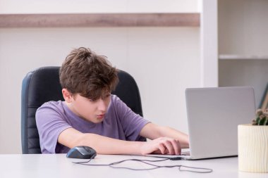 Okullu çocuk evde bilgisayar oyunu oynuyor.