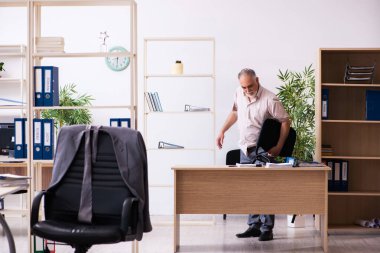 Eski erkek çalışan işyerinde fiziksel egzersiz yapıyor.