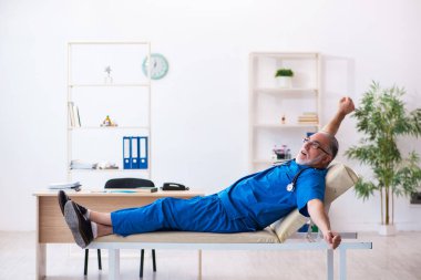 Yaşlı erkek doktor gece vardiyasından sonra çok yorgun.