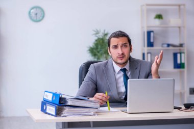 Ofisteki aşırı işten memnun olmayan genç bir erkek işçi.