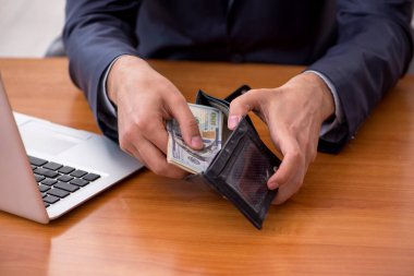 Genç bir erkek çalışanın cüzdanı ücret konseptinde tutuluyor.