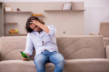 Genç adam evde alkol içiyor.