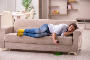 Genç adam evde alkol içiyor.