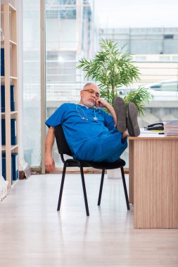 Klinikte çalışan yaşlı erkek doktor.