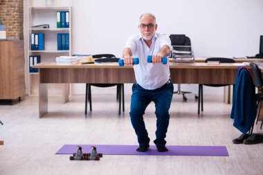 Ofiste spor egzersizleri yapan eski bir işadamı.