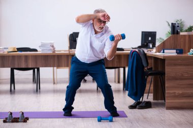 Ofiste spor egzersizleri yapan eski bir işadamı.