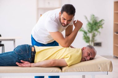 Yaşlı erkek hasta, genç erkek doktor masörünü ziyaret ediyor.