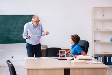 Yaşlı erkek öğretmen ve okul çocuğu sınıfta.