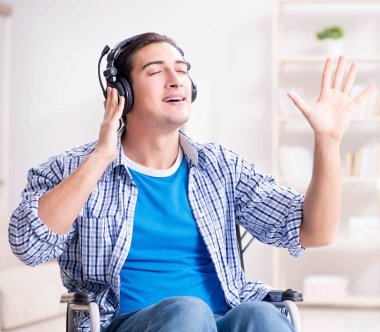 Tekerlekli sandalyede müzik dinleyen engelli adam.
