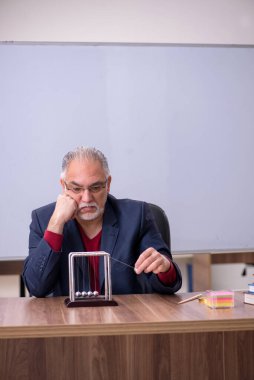 Sınıfta oturan eski bir fizikçi öğretmen.