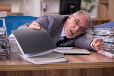 Ofisteki aşırı işten memnun olmayan yaşlı bir erkek işçi.