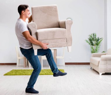 Genç adam evde mobilya taşıyor.