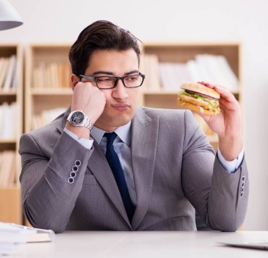 Aç komik iş adamı abur cubur sandviç yiyor.