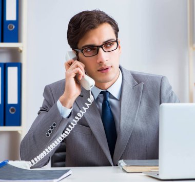 İşadamı ofis telefonundan konuşuyor.