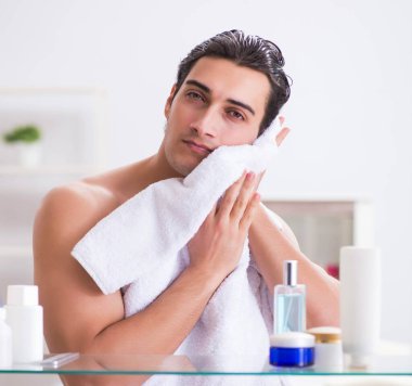 Genç adam banyoda çalışmak için hazırlanıyor.