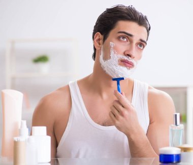 Genç yakışıklı adam sabah erkenden tıraş oluyor.