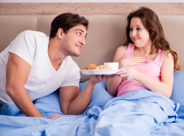 Mutlu bir aile yatakta kahvaltı yapıyor.