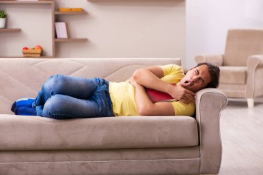 Evde kitap okuyan genç bir erkek öğrenci.