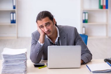 Ofisteki aşırı işten memnun olmayan genç bir erkek işçi.