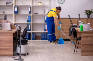 Genç müteahhit ofisi temizliyor.