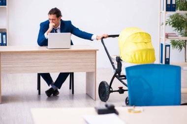 Genç erkek çalışan işyerinde çocuğa bakıyor.