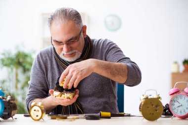 Atölyede çalışan yaşlı bir erkek saatçi.