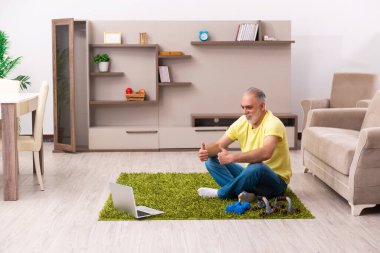 Yaşlı adam evde spor egzersizleri yapıyor.