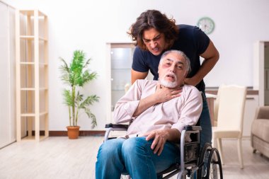 Tekerlekli sandalyedeki yaşlı adam ve genç kötü bakıcı.