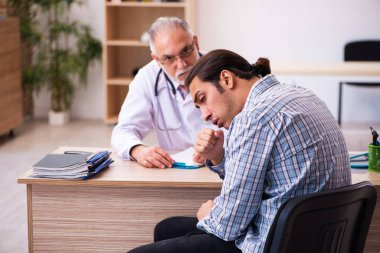 Genç erkek hasta yaşlı erkek doktoru ziyaret ediyor.