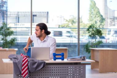 Genç erkek çalışan ofiste spor egzersizleri yapıyor.