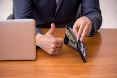 Genç bir erkek çalışanın cüzdanı ücret konseptinde tutuluyor.