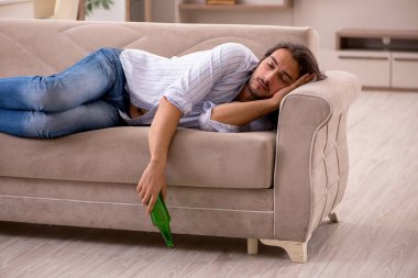 Genç adam evde alkol içiyor.