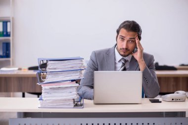 Ofisteki aşırı işten memnun olmayan genç bir erkek işçi.