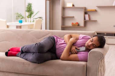 Genç adam salgın sırasında evde televizyon izliyor.