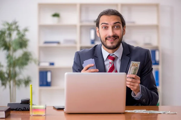 Young male employee playing cards at workplace