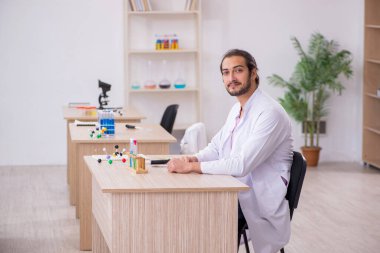 Sınıftaki masada oturan genç bir kimyager.