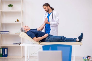 Yaşlı erkek hasta, genç erkek doktor masörünü ziyaret ediyor.