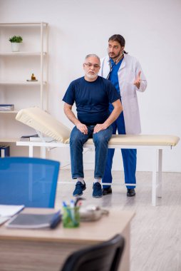 Yaşlı erkek hasta genç erkek doktoru ziyaret ediyor.