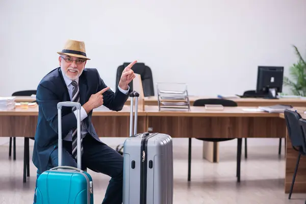 Old male employee preparing for travel in the office