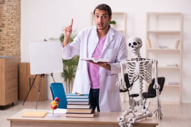 Sınıfta insan iskeleti üzerine çalışan genç bir erkek doktor.