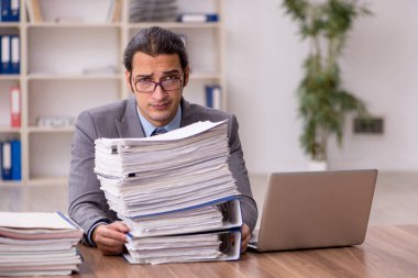 Ofisteki aşırı işten memnun olmayan genç bir erkek işçi.